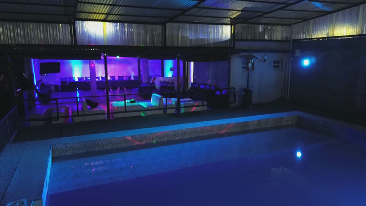 Pileta iluminada de noche con zona lounge al fondo