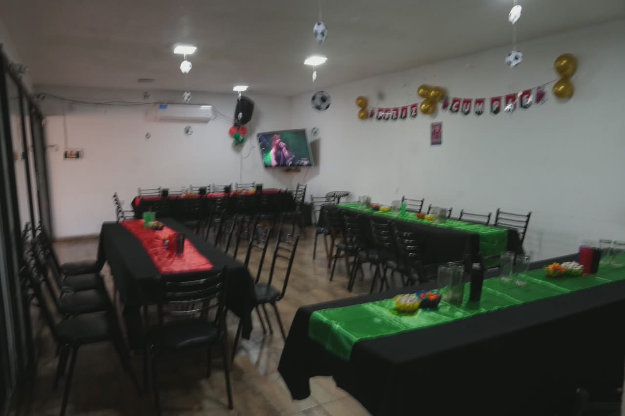Salón interior con mesas decoradas temática fútbol y banner Feliz Cumple